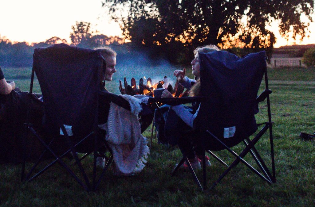 two girls chatting round a fire pit watching the sun set