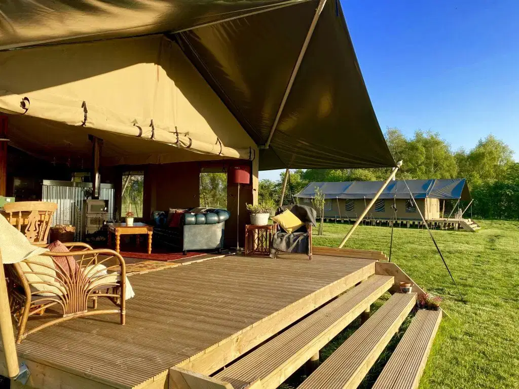 front opening of large safari tent revealing a sofa, table and chairs