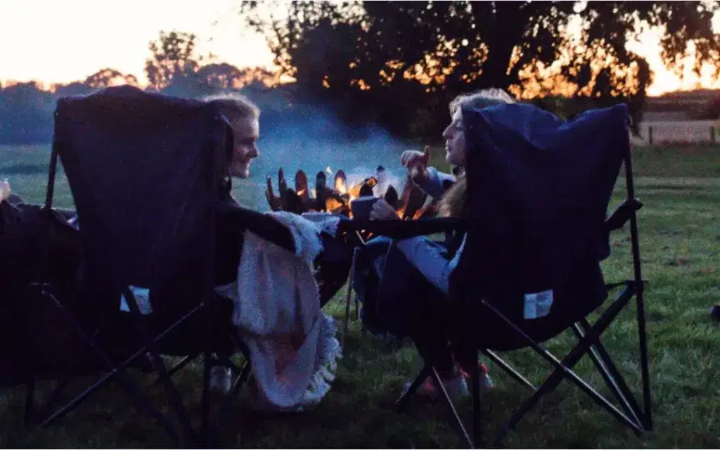two people chatting by a campfire