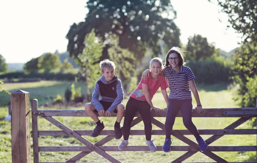 Three children sitting on a gate