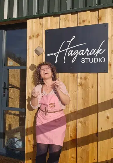 lady throwing clay in the air outside a pottery studio on a sunny day